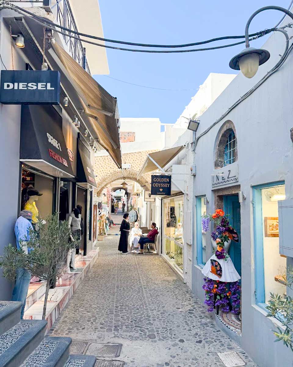Colorful cobblestone street lined with shops and cafes in Fira Santorini Greece