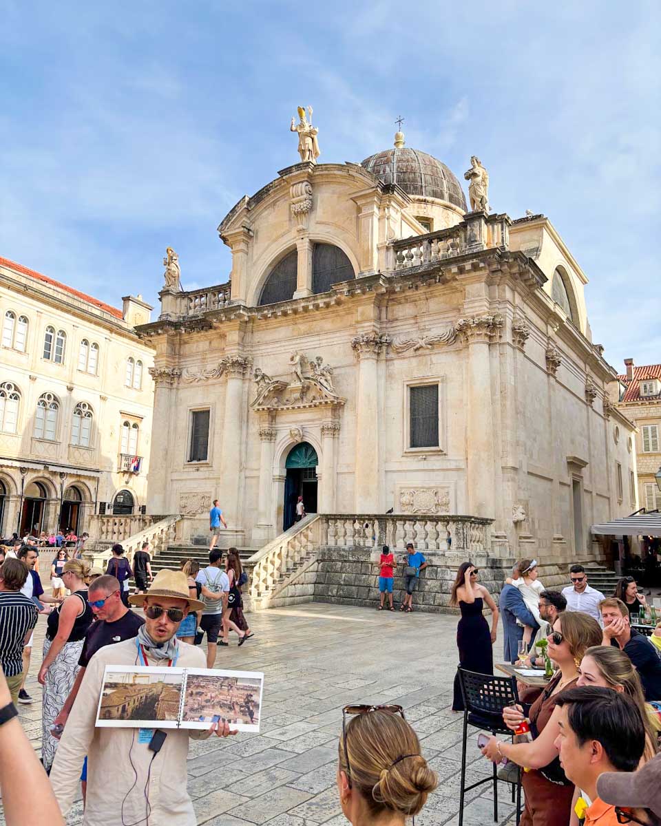 A guide hold up a photo where the scene was filmed on a Game of Thrones walking tour in Dubrovnik