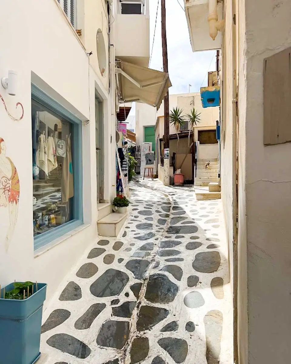 Narrow cobblestone alley in Chora Old Market, Naxos, Greece, lined with whitewashed buildings and boutique shops