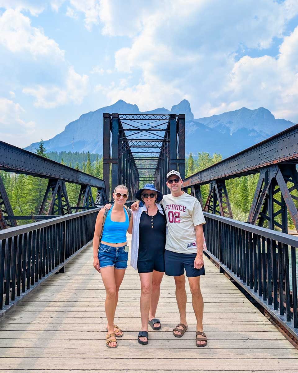 Bailey, Dan, and his mom pose for a photo on train bridge in Canmore