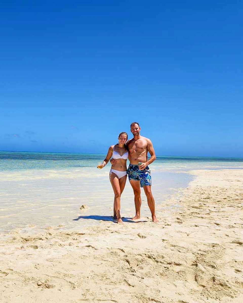 Bailey-and-Daniel-posing-for-a-picture-on-the-sand-with-turquise-blue-water-in-Fiji