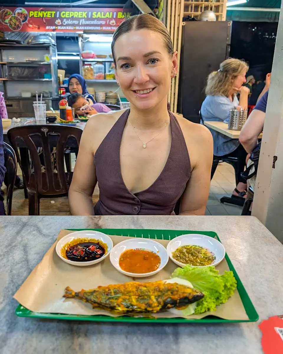 Bailey eating fish with sauces on a food tour in Kuala Lumpur, Malaysia