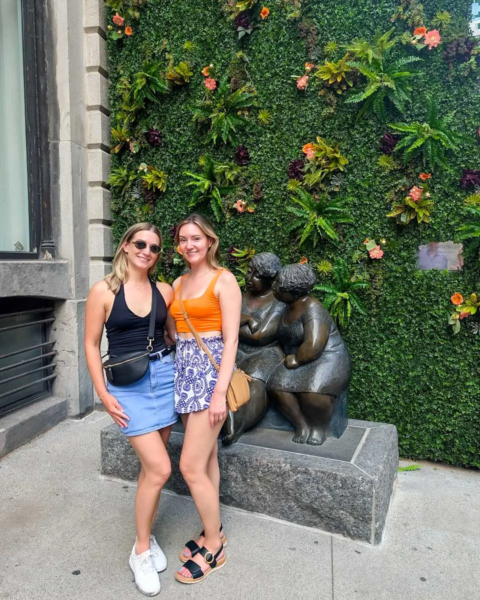 Bailey posing with her friend in front of a statue on a walking tour in Montreal, Quebec