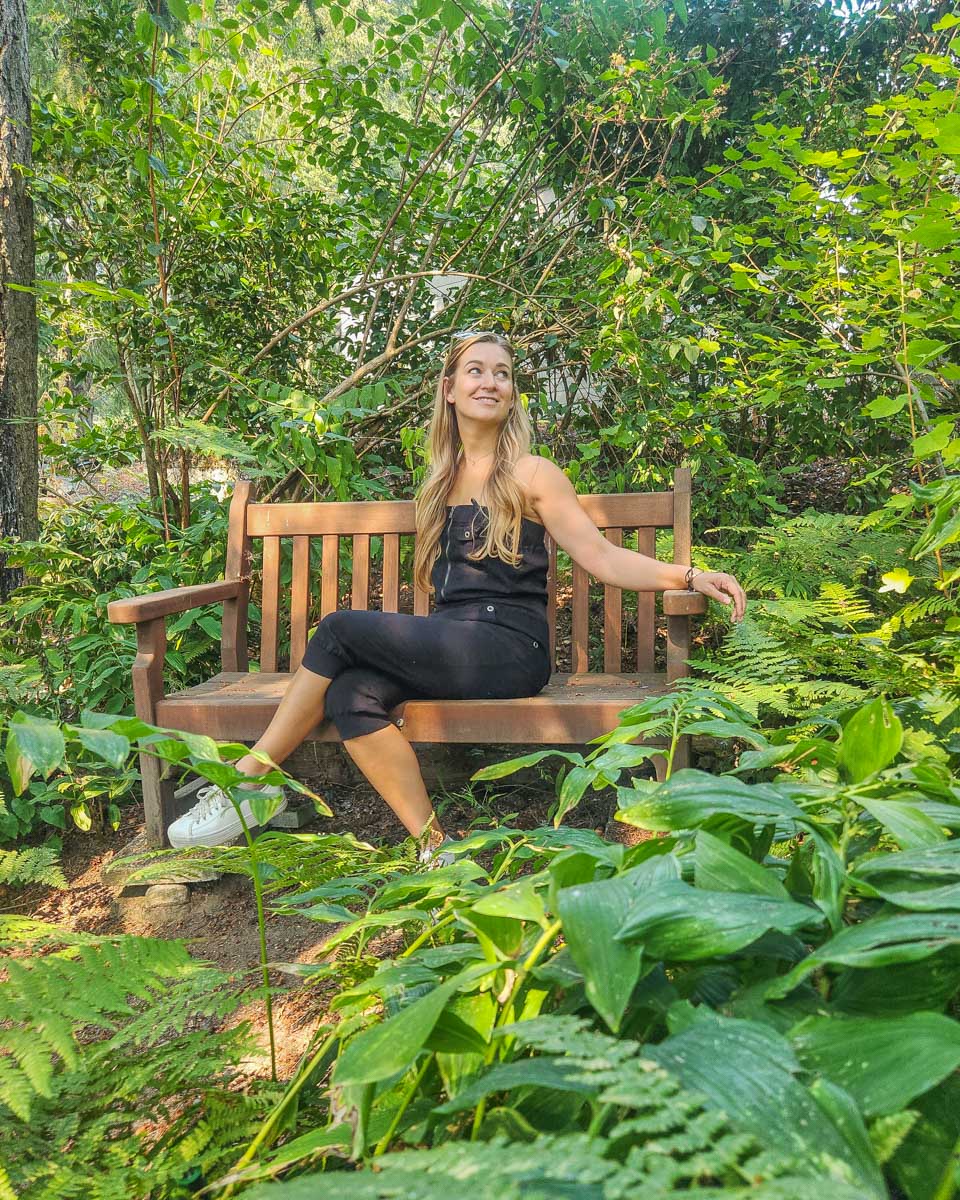 Bailey-sits-on-a-bench-surounded-by-greenery-at-the-gardens-in Halifax, Nova Scotia