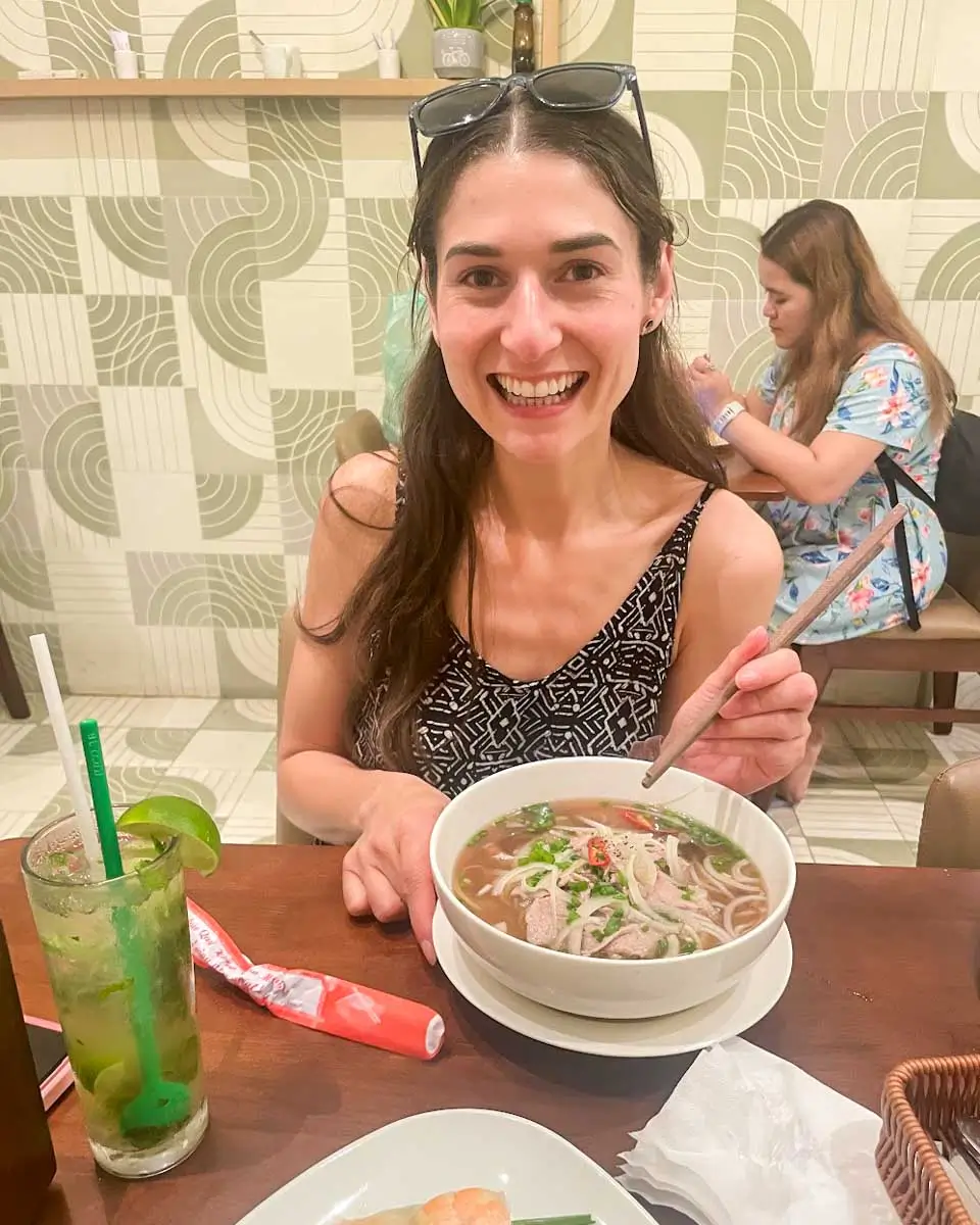 Brittni eating beef pho at a restaurant in Vietnam