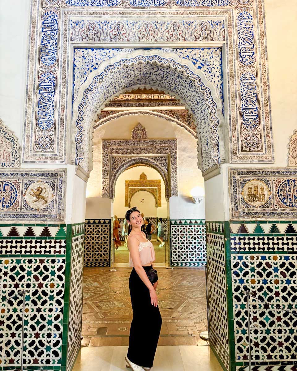 Brittni smiles for a photo in a tiled archway in the Royal Alcazar of Seville