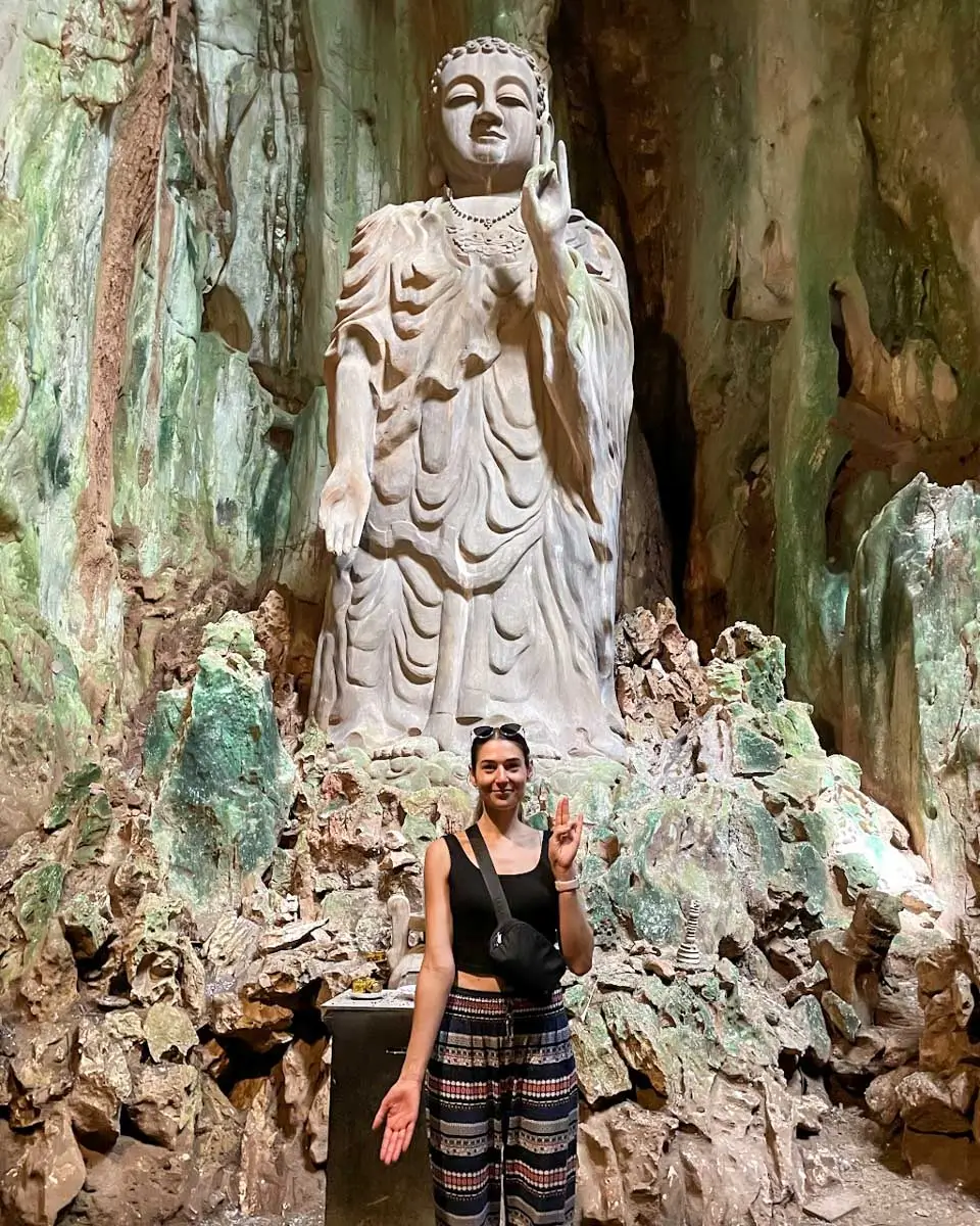 Brittni taking a photo in front of an old Buddha statue in Marble Mountains, Vietnam