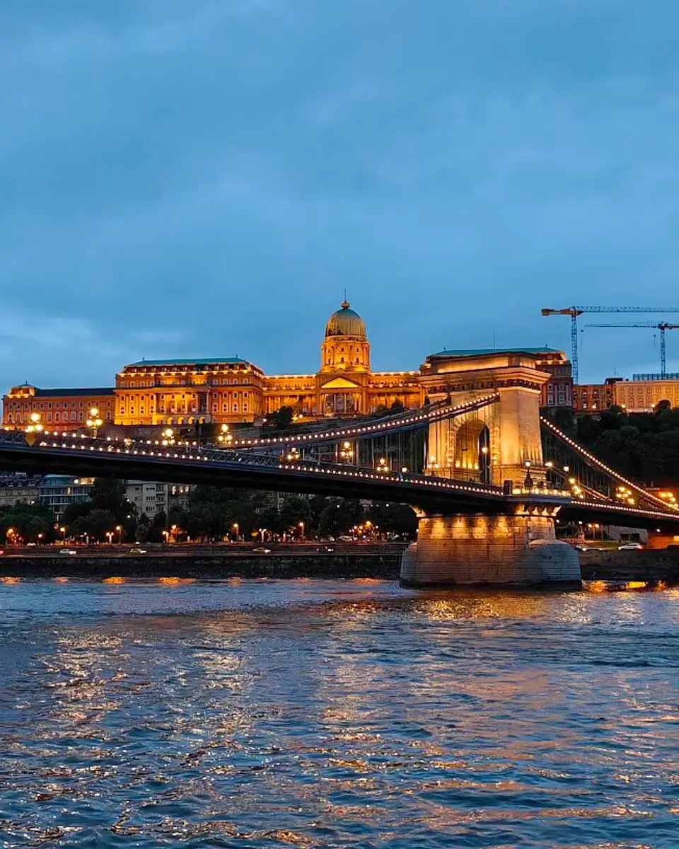 Buda Castle illuminated at night as seen from a Danube River dinner cruise in Budapest