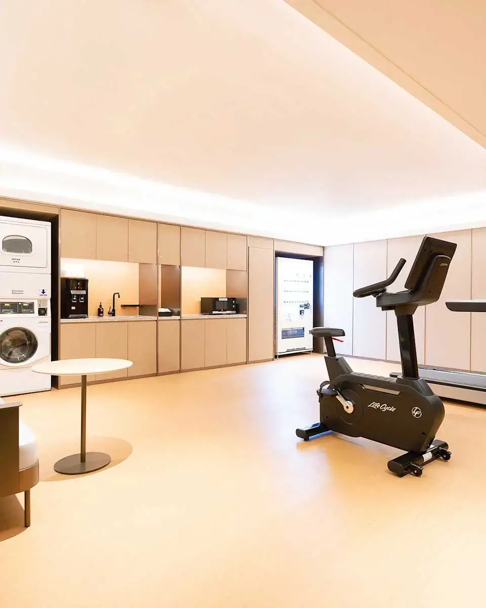 Modern gym and kitchenette area at JI Hotel Orchard Singapore with fitness equipment and a seating space