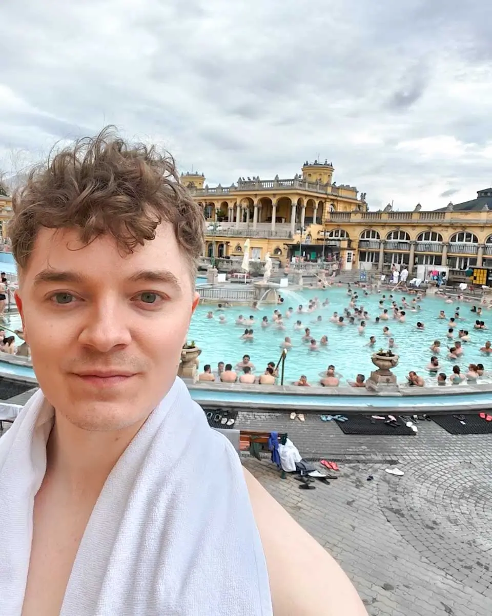 Luke taking a selfie at Széchenyi Thermal Bath with the outdoor pools in Budapest
