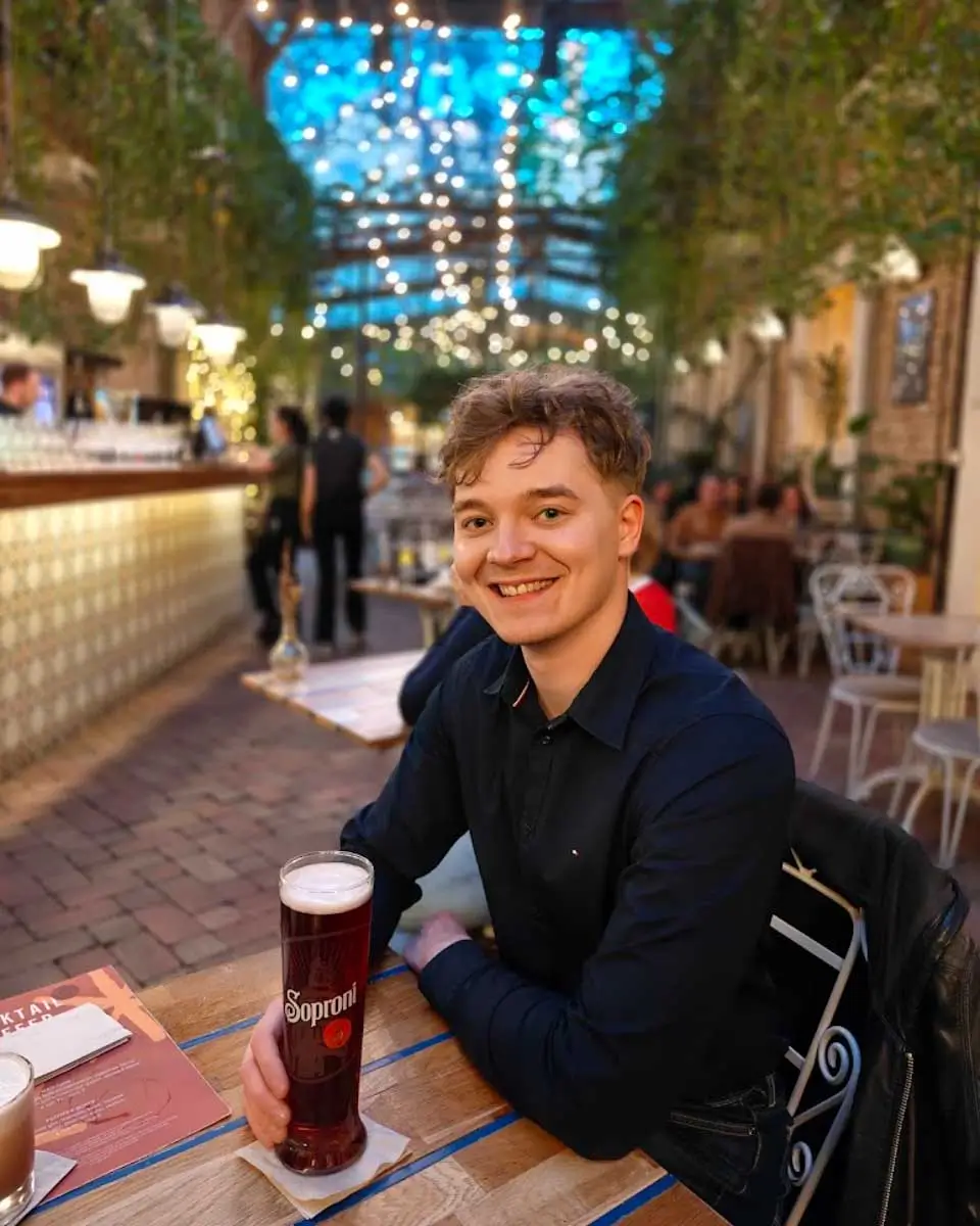 Luke drinking beer at Mazel Tov in Budapest