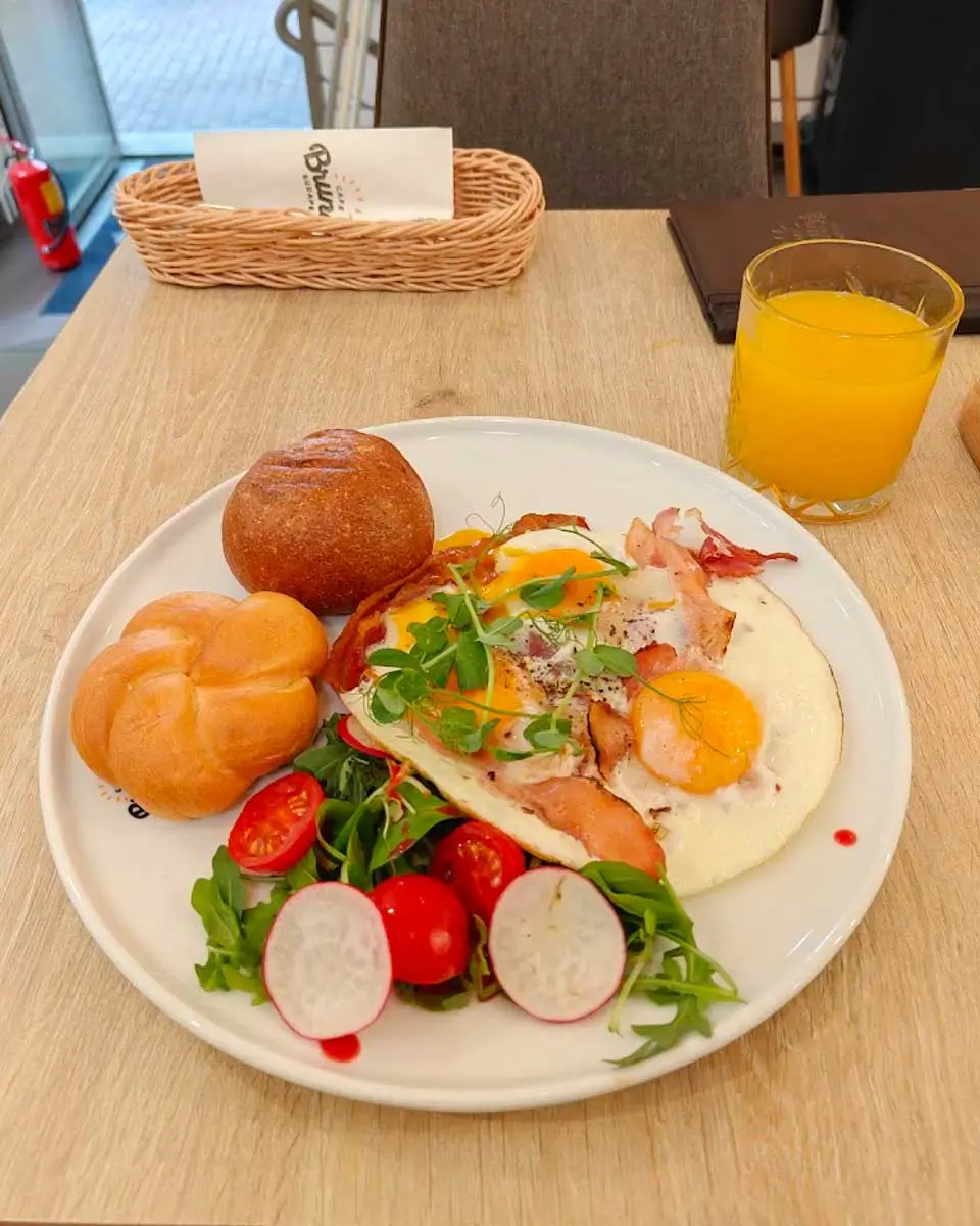 Breakfast spread with eggs, fresh fruit, buns, and juice served at Cafe Brunch in Budapest