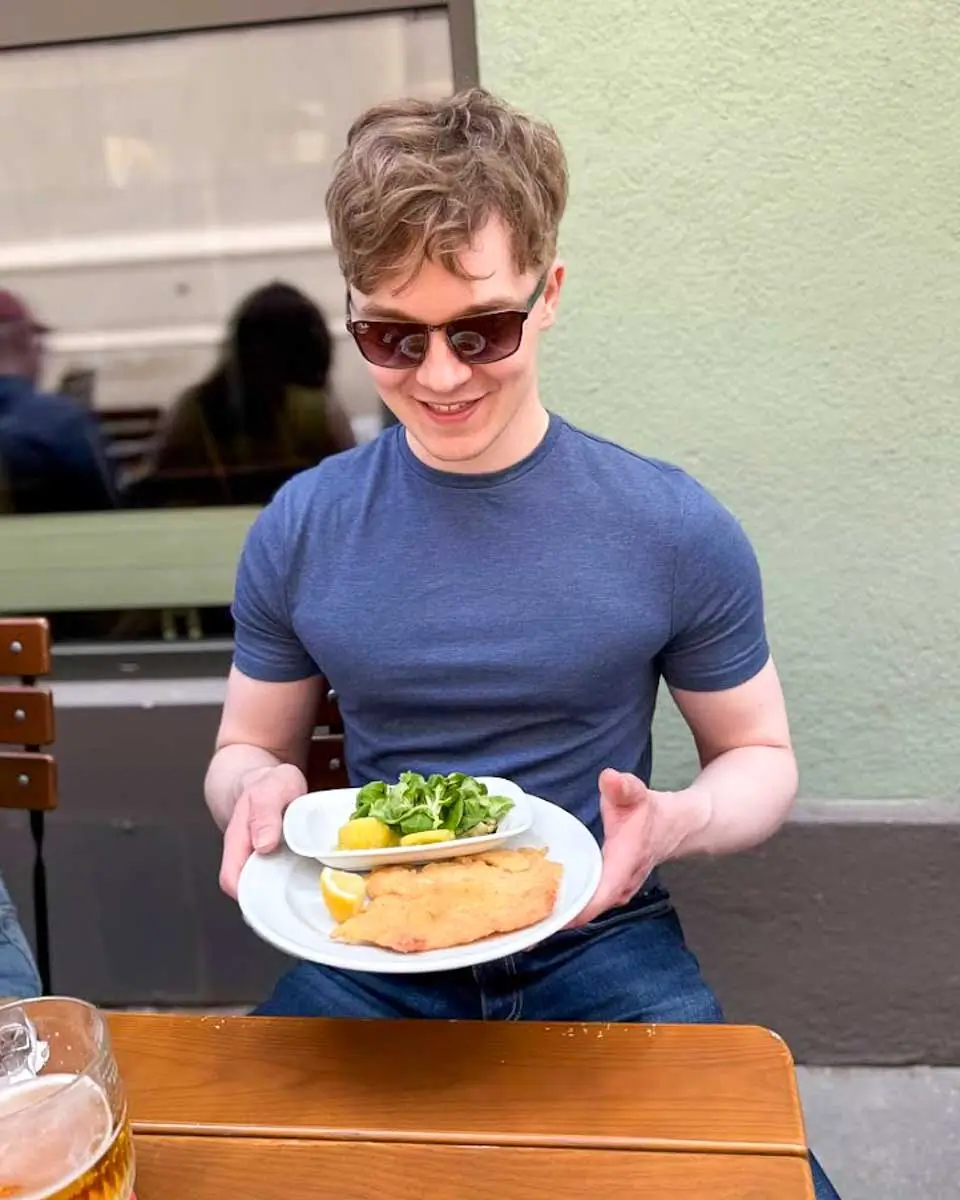 Luke eating wiener schnitzel during a Vienna food tour
