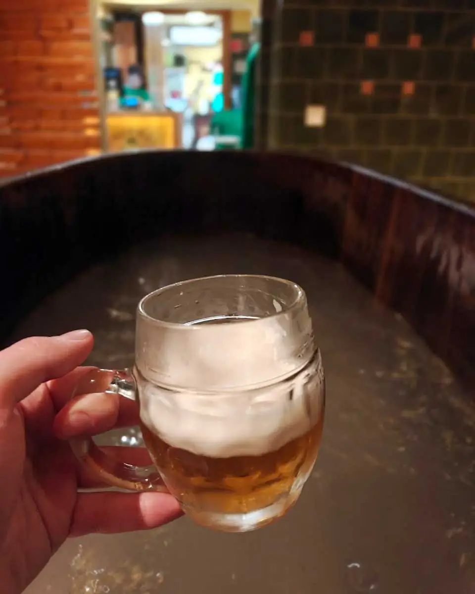 Luke holding a beer while relaxing in a wooden bath tub at Beer & Spa in Budapest