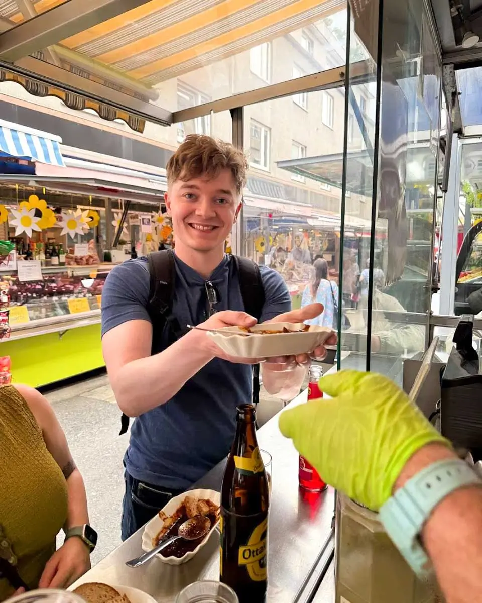 Luke sampling local food during a food tour in Vienna
