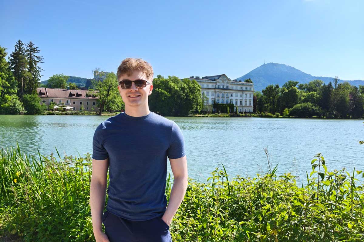 Luke smiles in front of a lake in Salzburg, Austria