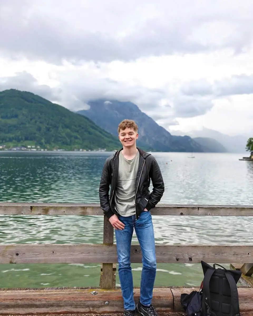 Luke standing by Lake Hallstatt with the Austrian Alps in the background
