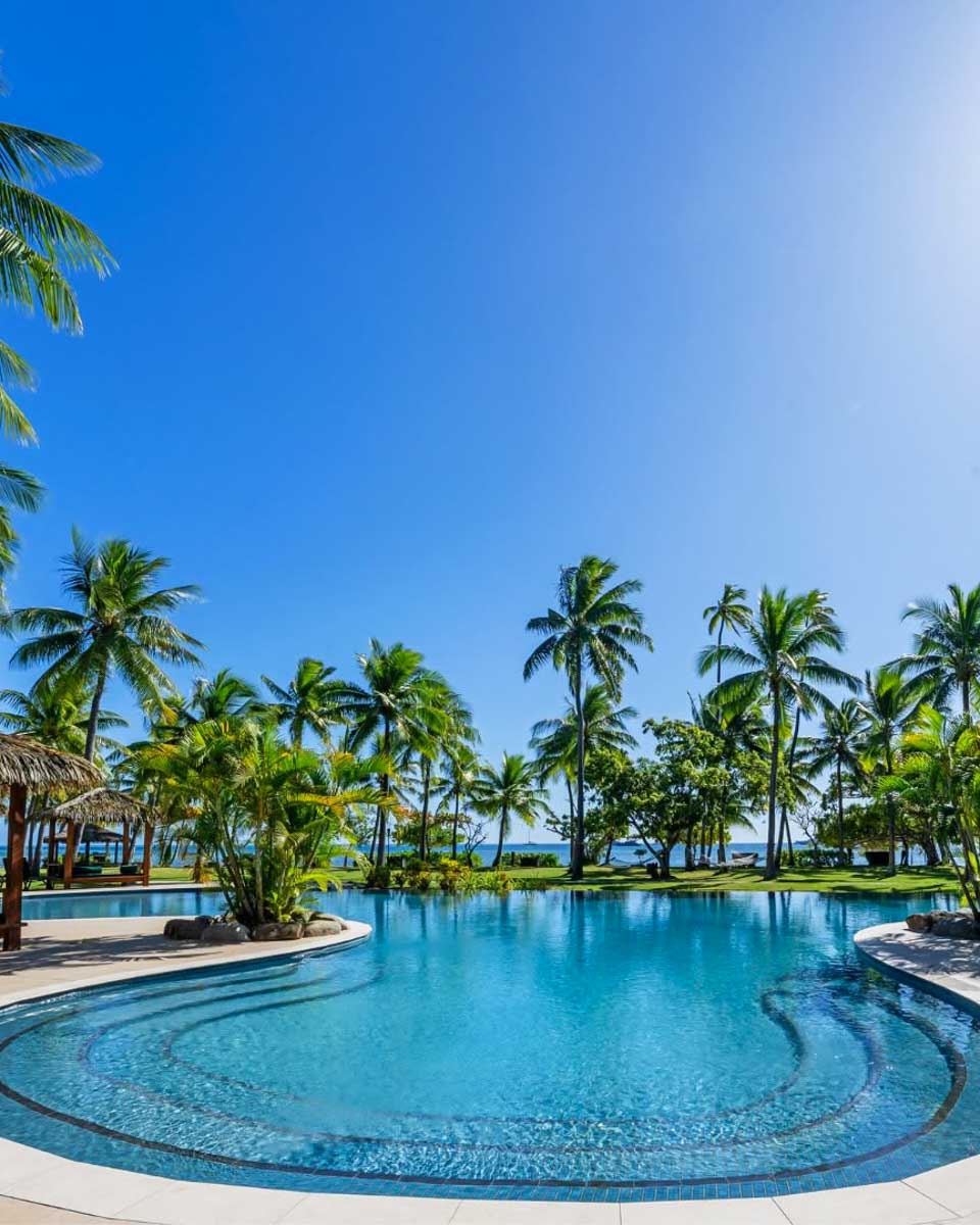 The outdoor pool area with palm trees at Lomani Island Resort & Spa in Fiji