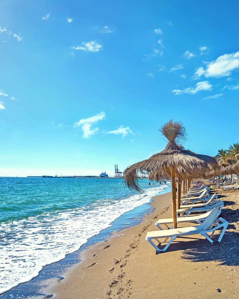 A beach with lounge chairs in Malaga, Spain