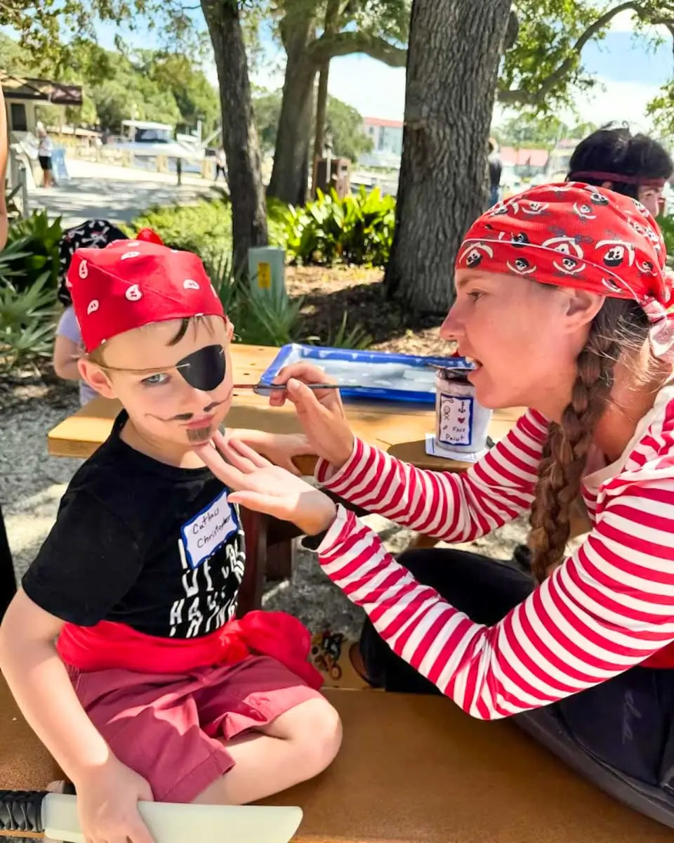 A woman painting a child's face on a Pirates of Hilton Head tour, USA
