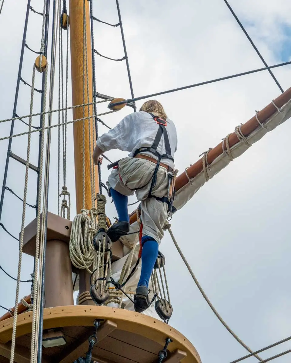 An actor climbs a replica ship in Historic Jamestown Settlement on a tour from Williamsburg, Virginia