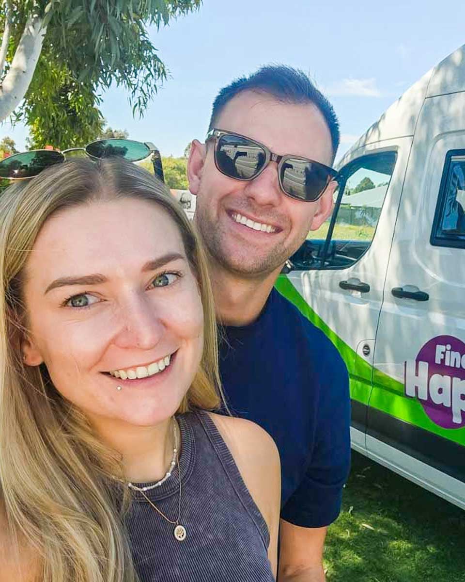 Bailey and Daniel smiling in front of their JUCY campervan in Australia