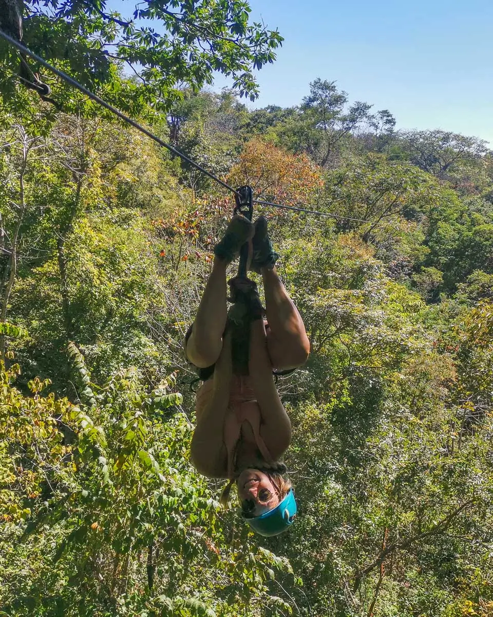 Bailey ziplining upside down in Roatan’s jungle in Honduras