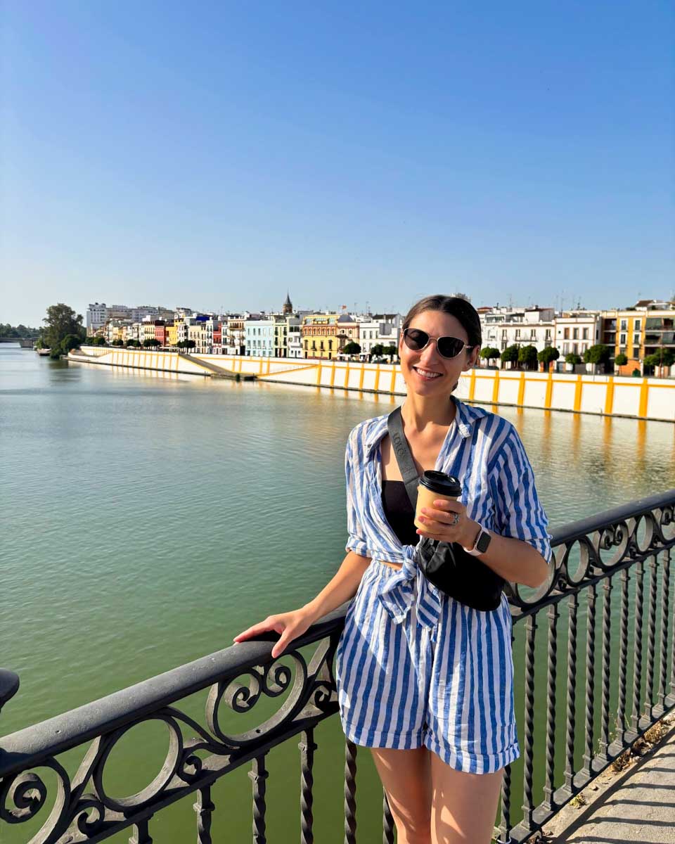 Brittni poses for a photo on the Triana Bridge with the Triana area behind her in Seville