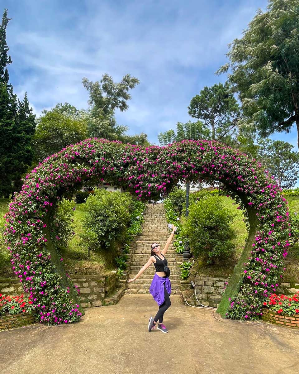 Brittni poses for a photo under a flower arch in the Dalat Gardens