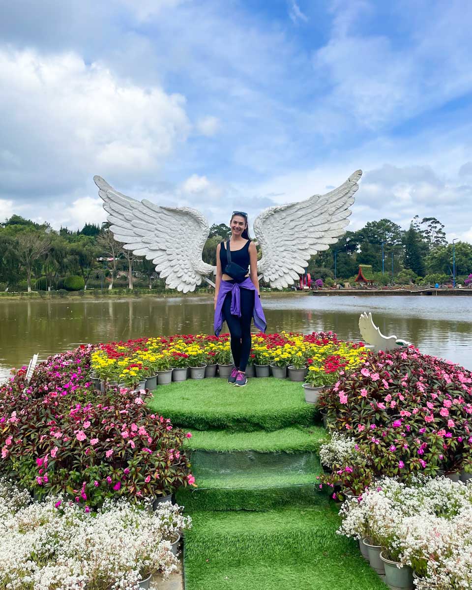 Brittni poses for a photo with angel wings behind her at the Dalat Gardens