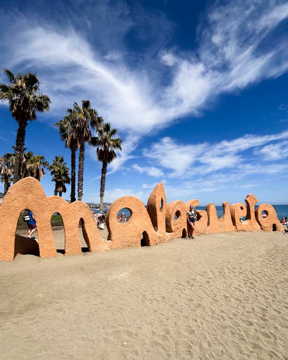 Brittni poses in front of the Playa de la Malagueta sign in Malaga