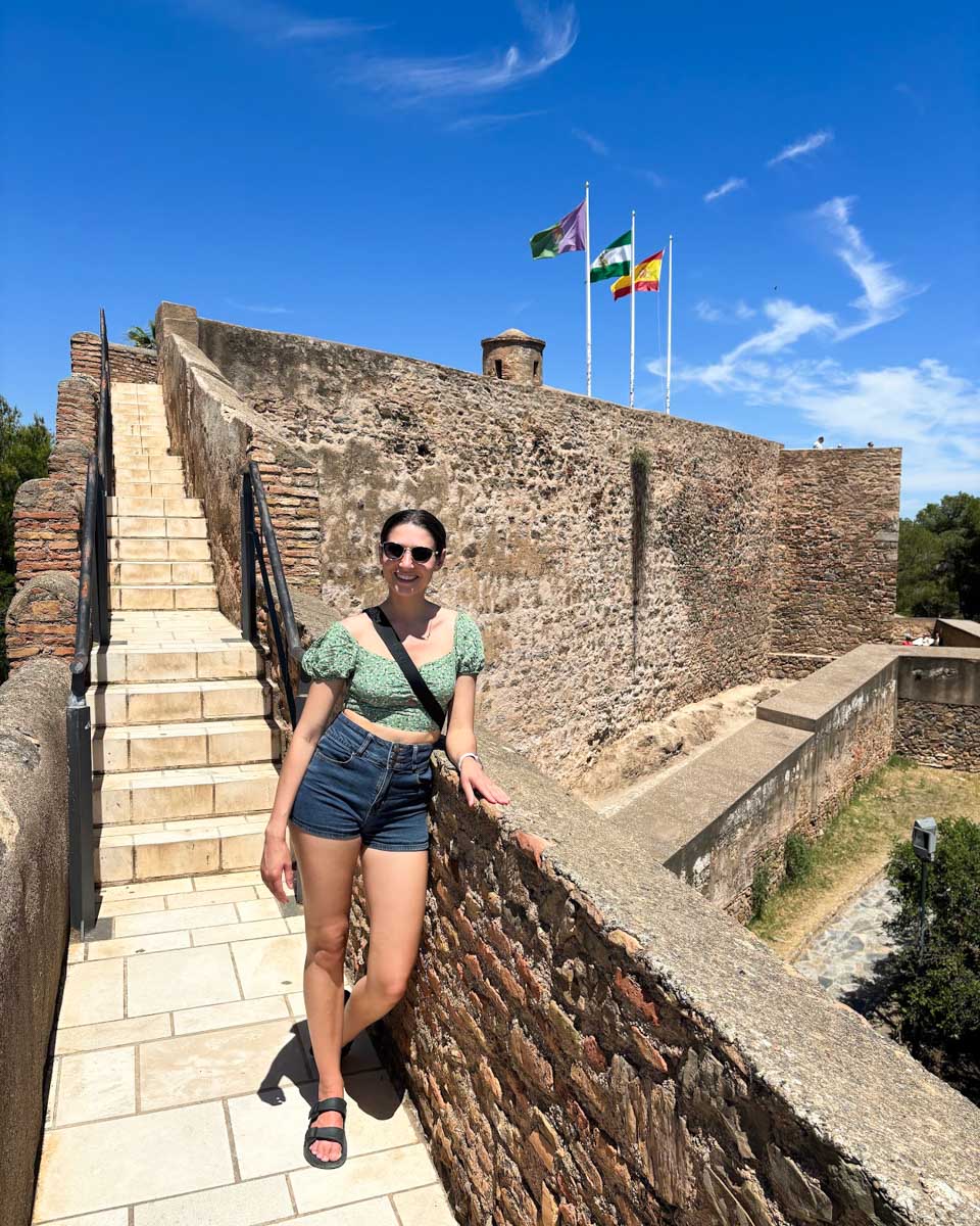 Brittni poses walking along the wall of Gibralfaro castle in Malaga