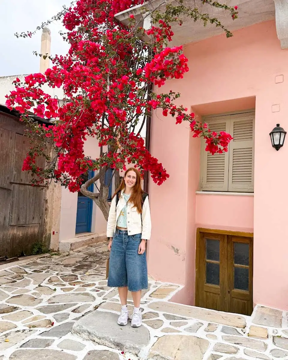 Hannah standing outside a pink colored house in Naxos, Greece