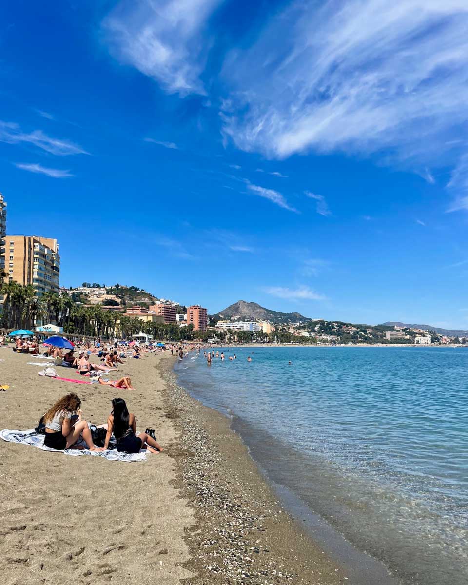 People relax on the beach at Playa de la Malagueta in Malaga