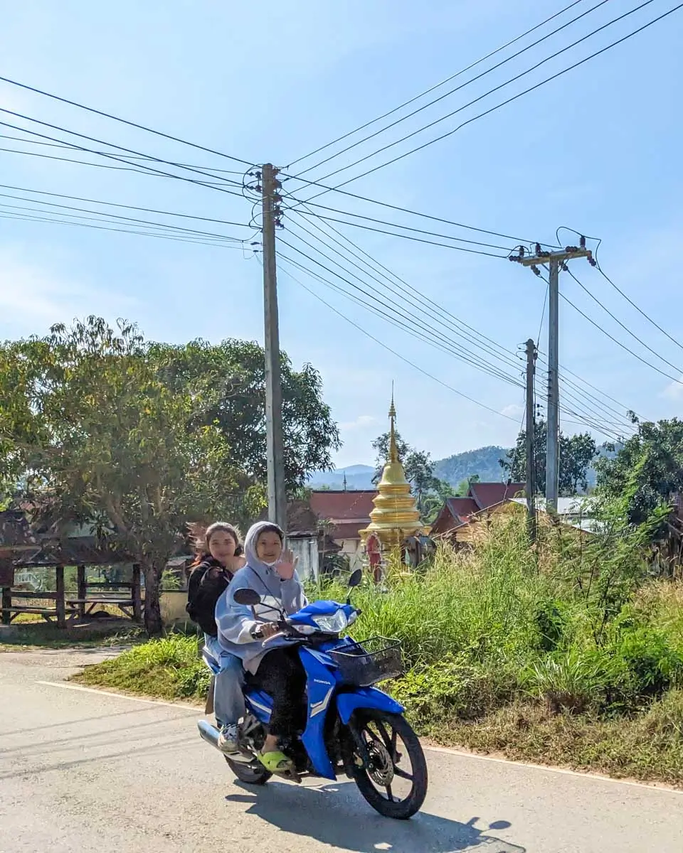 Two people smile on a motorbike in Pai, Thailand