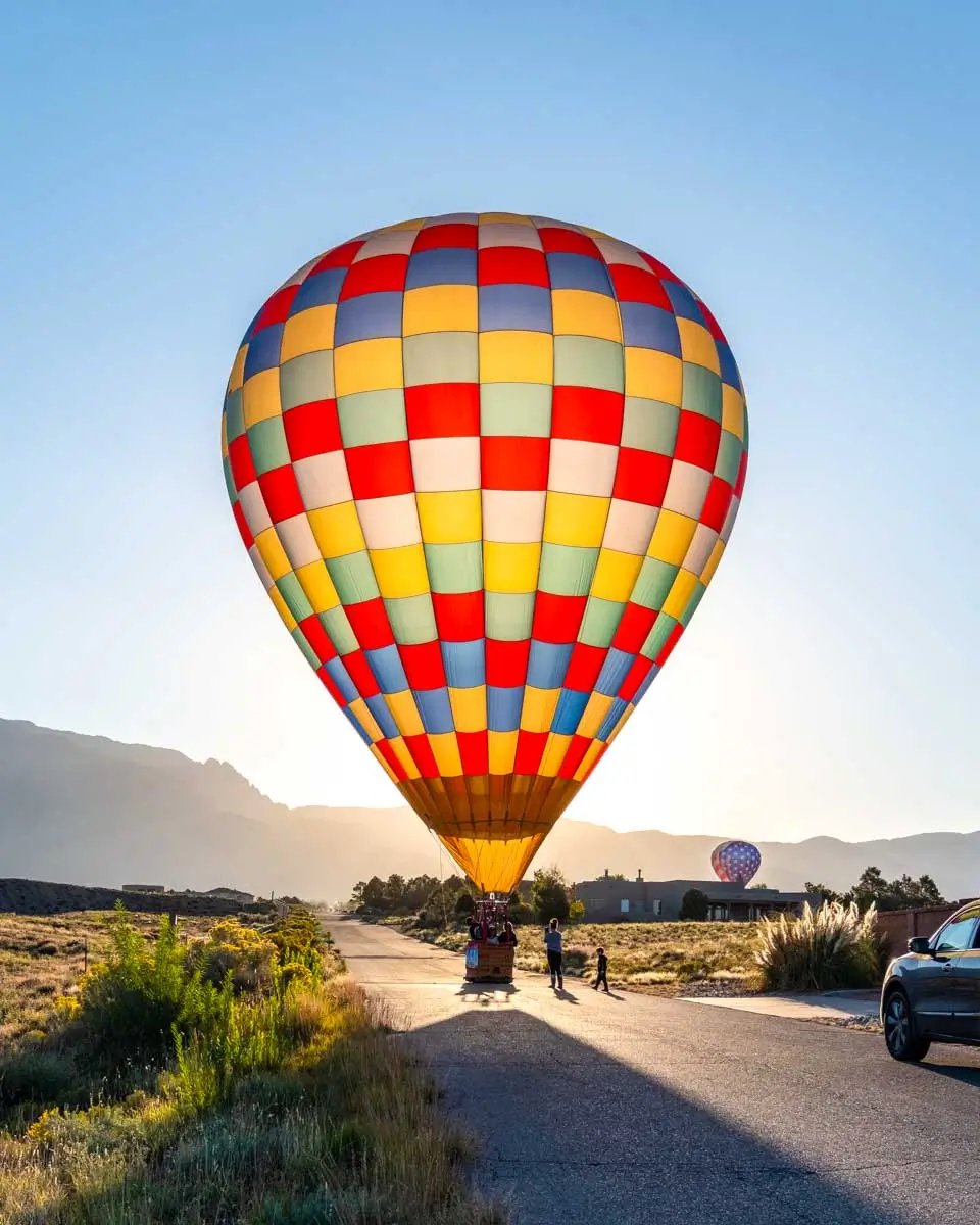 A colorful hot air balloon lands on a road in Albuquerque, New Mexico