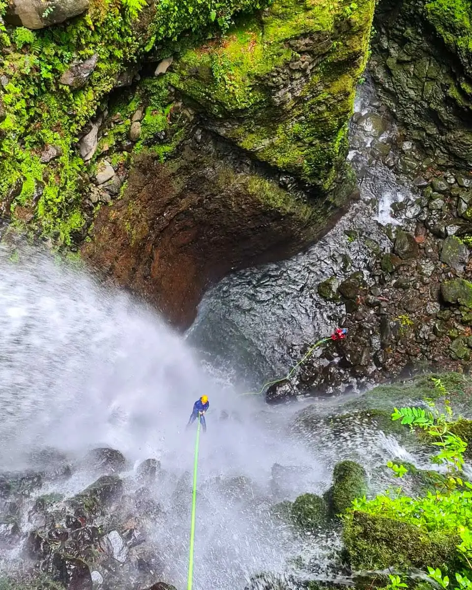 A man going down the waterfall on a level 2 canyoning tour in Madeira, Portugal