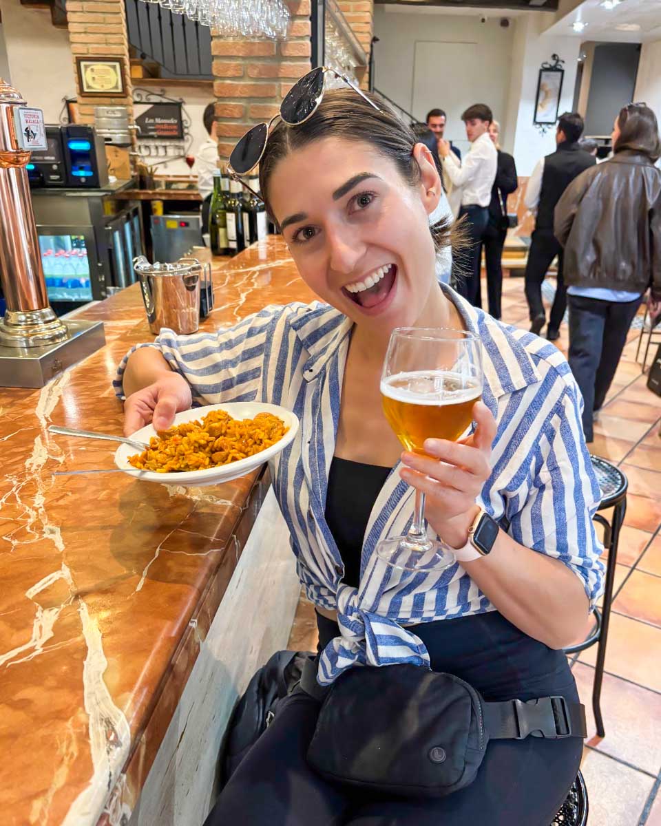 Brittni holds up her beer and plate of tapas in Granada, Spain