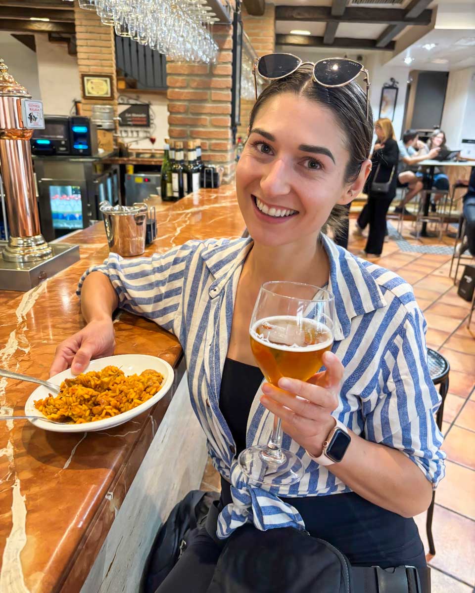 Brittni smiles with beer and tapas in Granada, Spain