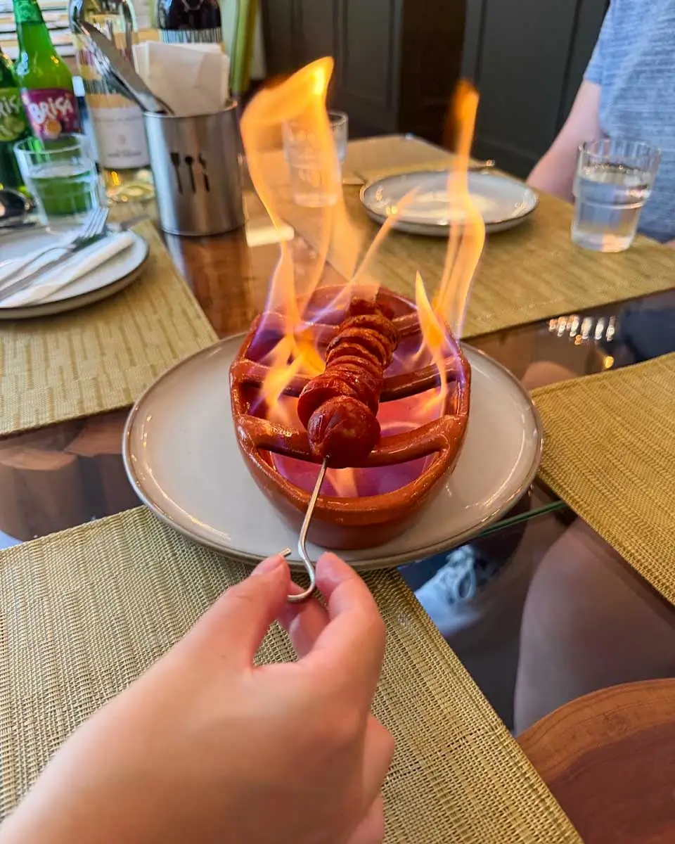 Hannah having flaming chorizo on a food tour in Madeira, Portugal