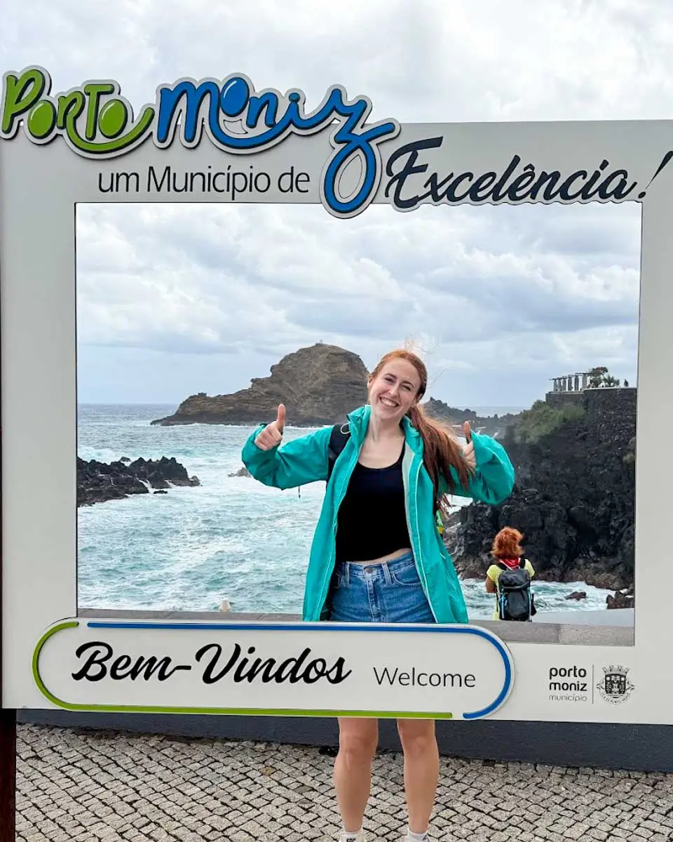 Hannah taking a photo with Porto Muniz sign in Madeira, Portugal