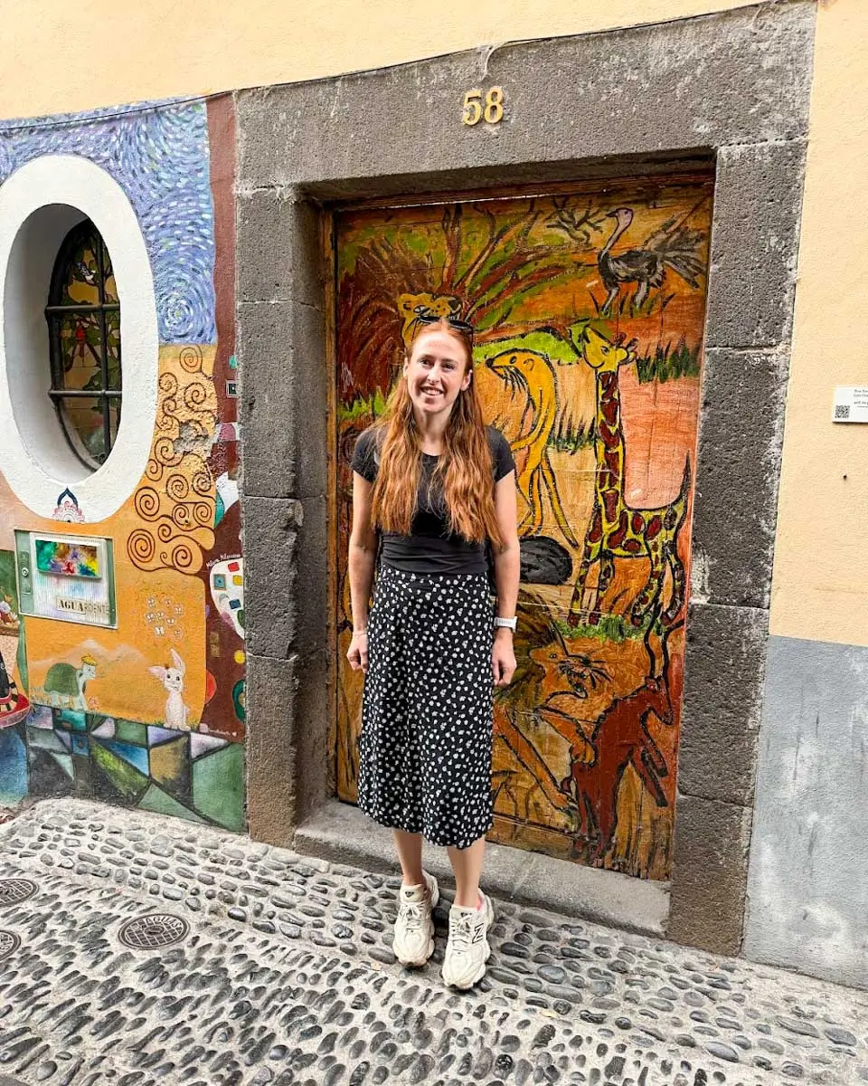 Hannah taking photo outside a painted door at Rua de Santa Maria Street, Madeira, Portugal