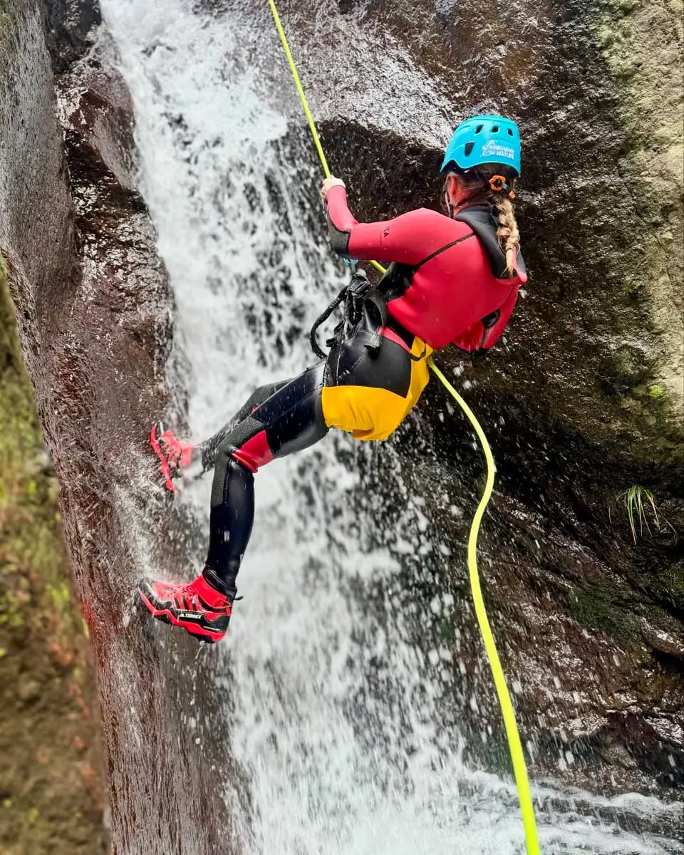 a woman canyoning down the waterfall in Funchal Ecological Park, Madeira, portugal